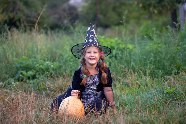niña feliz con calabaza al aire libre en Halloween
 - Foto, Imagen