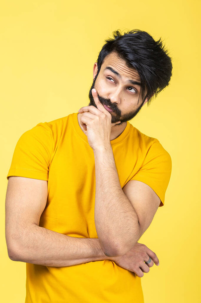 Emotional portrait of a Hindu man in a yellow T-shirt on a bright orange background - Photo, Image
