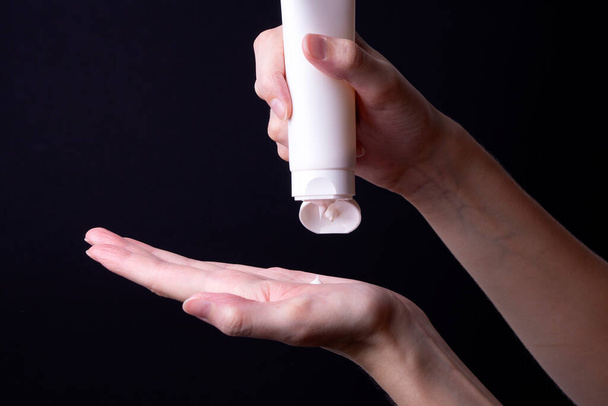 una mujer se aplica una crema o loción en la mano - Foto, imagen