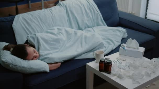 Osoba z chorobą śpiąca owinięta w koc na sofie - Materiał filmowy, wideo