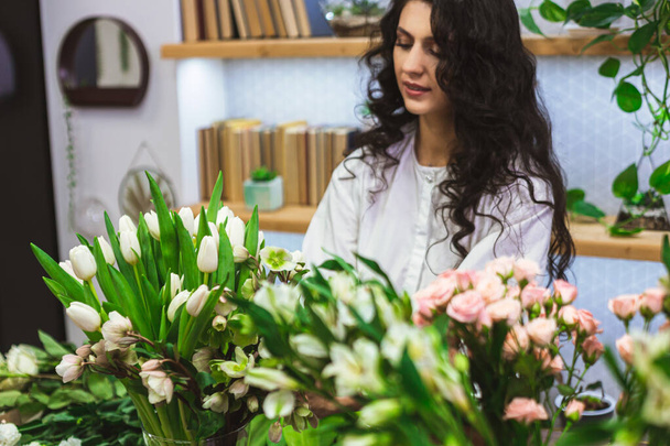 Attractive young woman florist is working in a flower shop. - Foto, immagini