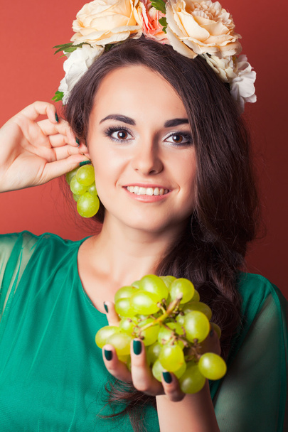 Woman wearing wreath and holding green grapes - Фото, зображення