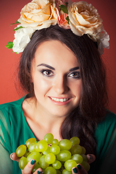 Woman wearing wreath and holding green grapes - Фото, зображення
