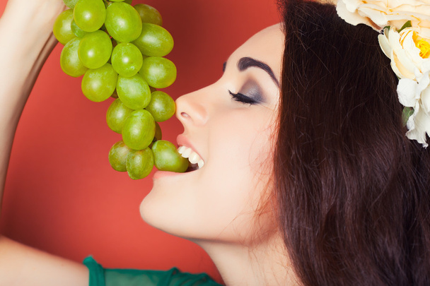 Woman wearing wreath and holding green grapes - Foto, imagen