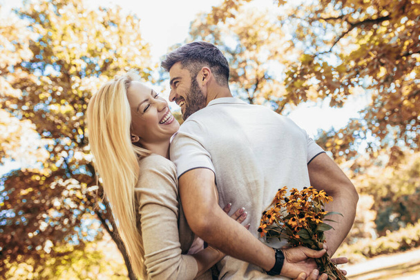 Amar pareja joven en una cita con flores en el parque - Foto, Imagen