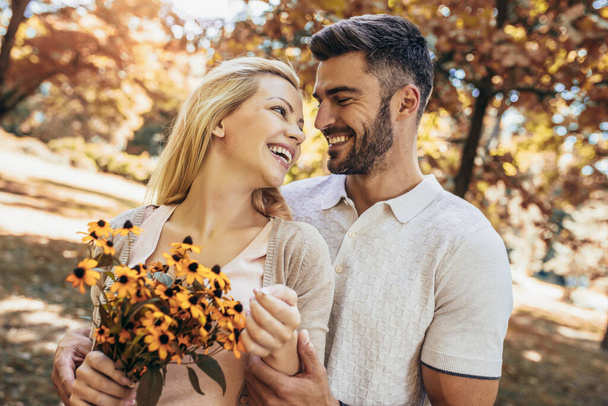 Amar jovem casal em um encontro com flores no parque - Foto, Imagem