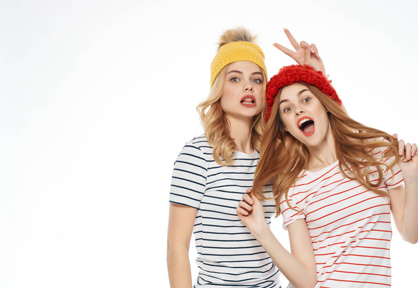 due donne che si abbracciano in berretti amicizia emozioni luce sfondo - Foto, immagini