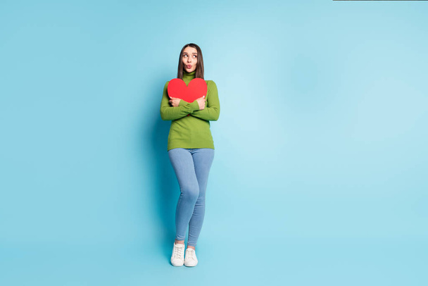 Photo of excited affectionate lady hug red paper heart figure look empty space wear green turtleneck isolated on blue background - Fotoğraf, Görsel