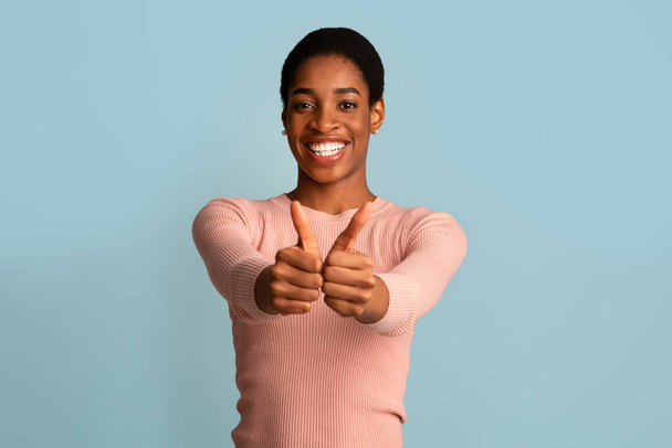 Goed gedaan. gelukkig vrolijke zwarte vrouw tonen duimen omhoog bij camera - Foto, afbeelding