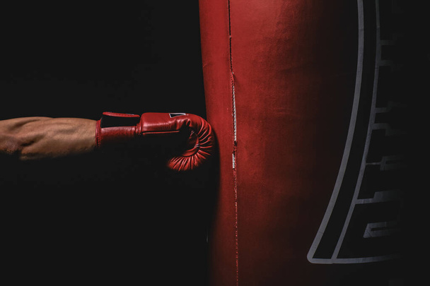 赤のボクシンググローブは、赤のボクシングバッグをパンチ. - 写真・画像