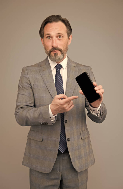 Man επίσημη διευθυντής ρούχα δείχνει την οθόνη του κινητού, την εφαρμογή ενημέρωση έννοια - Φωτογραφία, εικόνα
