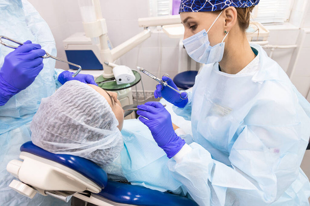 Dentistry concept. Professional dental services and modern equipment without pain. A doctor with an assistant treats the patients teeth and gives an anesthetic injection - Foto, Bild
