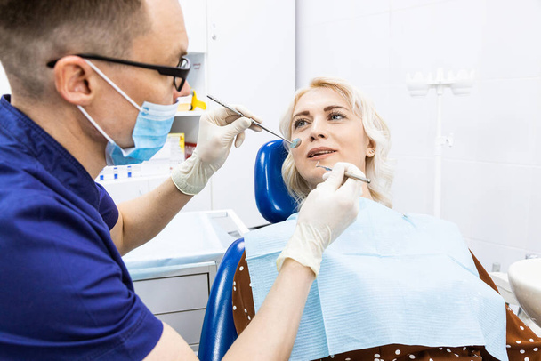 Dentistry concept. Professional dental services and modern equipment without pain. The doctor consults and treats the woman, conducts an examination and draws up a treatment plan - Foto, Imagem