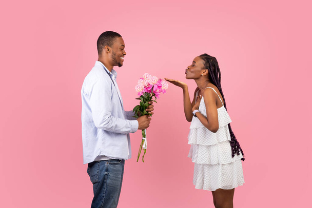 zwart vrouw blazen man kussen, guy holding bloemen - Foto, afbeelding