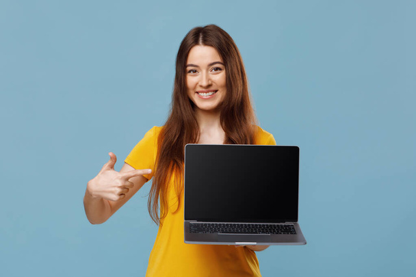 Happy young lady pointing at notebook with empty screen, mockup - Photo, Image