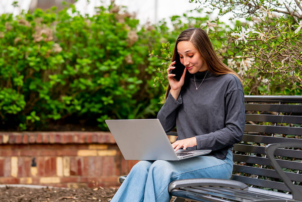 Wspaniała brunetka modelka pracuje na swoim komputerze na zewnątrz, ciesząc się wiosenną pogodą - Zdjęcie, obraz