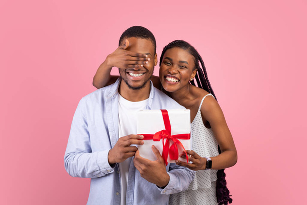 Happy black lady making surprise for her boyfriend giving box - Photo, Image