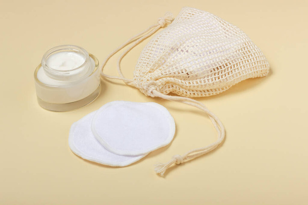 Cotton reusable makeup remover pads in a cloth bag on a beige background. The concept of ecology and conscious consumption. Reusable cotton pads - Valokuva, kuva
