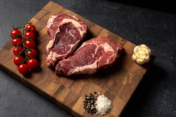 Raw marbled beef steak on a wooden cutting board - Фото, изображение