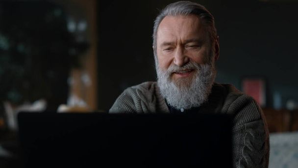 Γενειοφόρος γέρος που έχει υπολογιστή βιντεοκλήσης σε εσωτερικούς χώρους. Ανώτερος επιχειρηματίας που χρησιμοποιεί PC. - Φωτογραφία, εικόνα