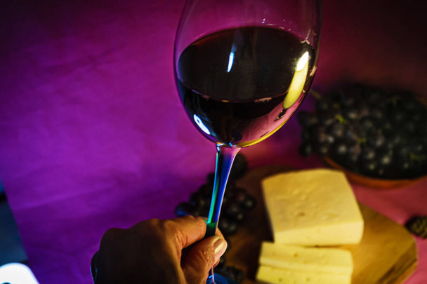 A glass of red wine with cheese and grapes close-up on a purple background - Φωτογραφία, εικόνα