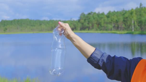 Mulher segurando garrafa de plástico perto do lago.Mudança climática e conceito de poluição - Filmagem, Vídeo