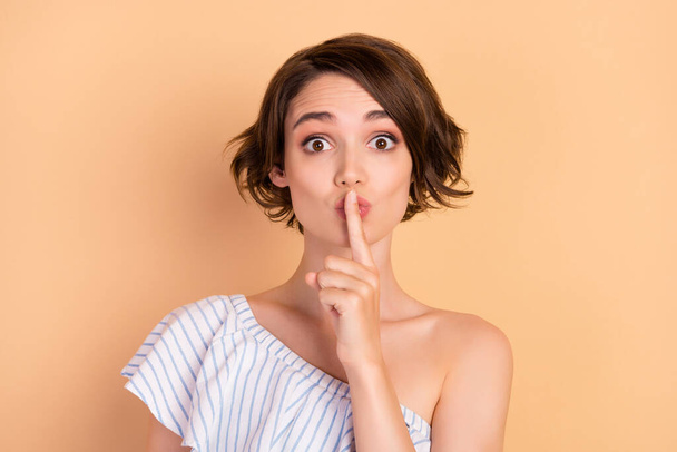 Photo of young attractive girl cover lips finger shh keep secret confidential isolated over beige color background - Foto, afbeelding
