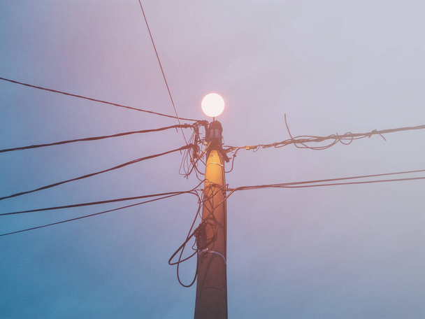 Des lignes électriques dans la ville. Câbles électriques fixés à un poteau électrique de rue sous le ciel bleu. - Photo, image