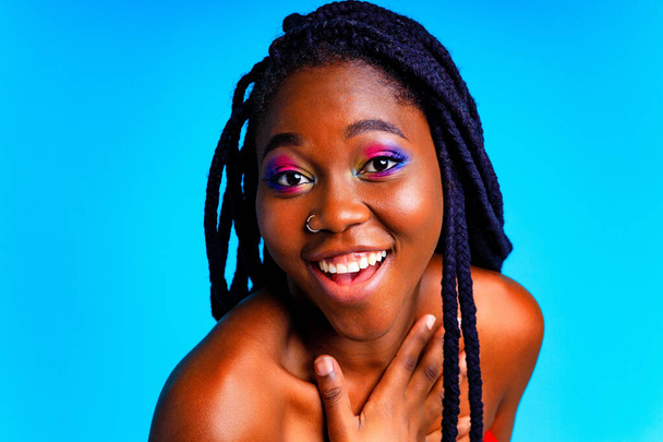 african american woman with gorgeus bright color make up feels proud and self confident in blue wall studio background - Фото, зображення