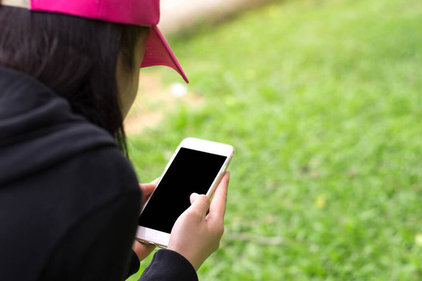 Fermez les mains féminines tenant l'écran noir de téléphone intelligent pour l'espace de copie avec le champ d'herbe arrière-plan flou. Concentration sélective. - Photo, image
