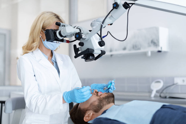 Kobieta stomatolog przy użyciu mikroskopu stomatologicznego w nowoczesnej klinice - Zdjęcie, obraz