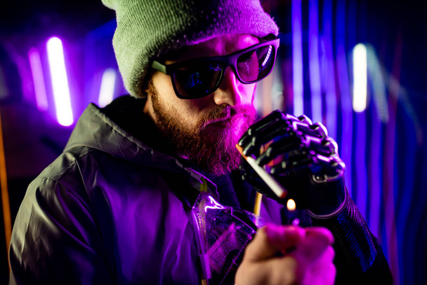 cyber robot hand close up of male handle use lighters going to smoking a cigarette in neon studio - 写真・画像