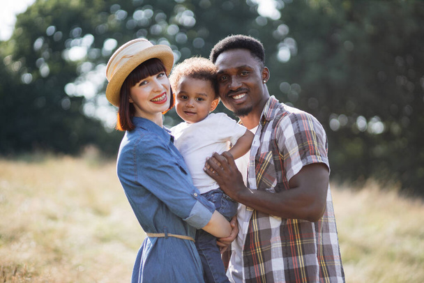 Cheerful multicultural parents hugging little son outdoors - Valokuva, kuva