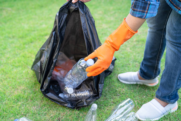Asyalı kadın gönüllü olarak parkta çöp poşetlerine su plastik şişeleri taşıyor, çöpleri parka atıyor, çevresel ekoloji kavramını geri dönüştürüyor.. - Fotoğraf, Görsel