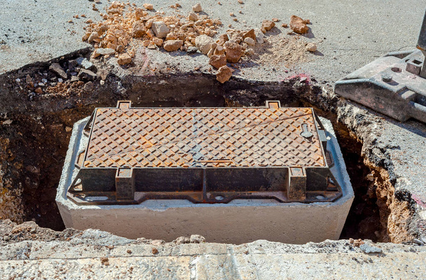 beton kokpitowy i właz żeliwny umieszczone przed zamknięciem wykopu i odbudową drogi - Zdjęcie, obraz