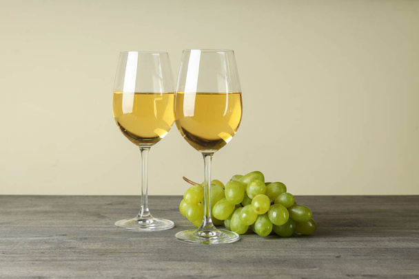 Gri dokulu masada beyaz şarap ve üzüm kadehleri. - Fotoğraf, Görsel