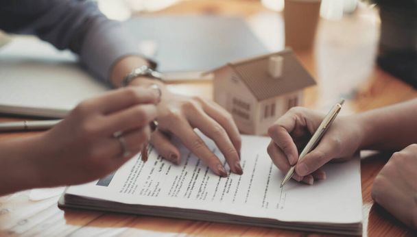 Immagine ritagliata dell'agente immobiliare che assiste il cliente a firmare la carta del contratto alla scrivania con modalità casa - Foto, immagini
