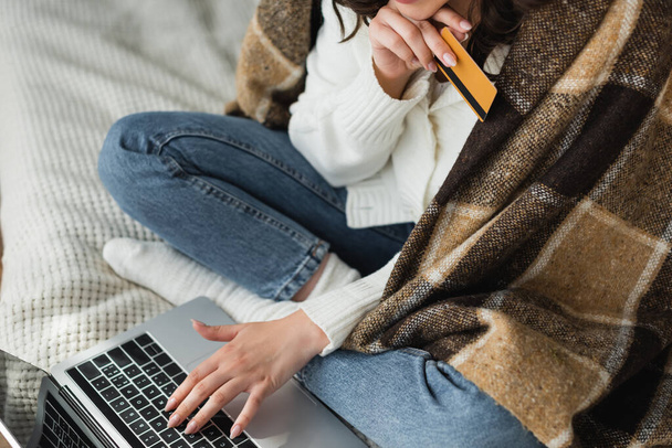 обрезанный вид женщины с кредитной картой, печатающей на ноутбуке на кровати - Фото, изображение