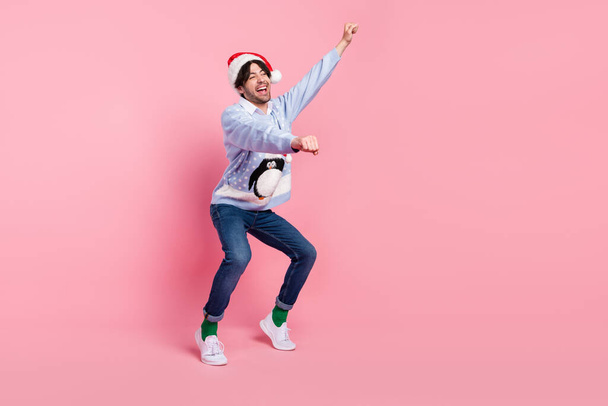Photo of funny pretty young man dressed blue christmas pullover dancing riding horse smiling isolated pink color background - Фото, зображення