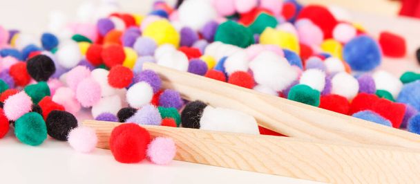 Small fluffy colorful pompoms and wooden tongs. Development of kids motor skills, coordination, creativity and logical thinking - Foto, Bild