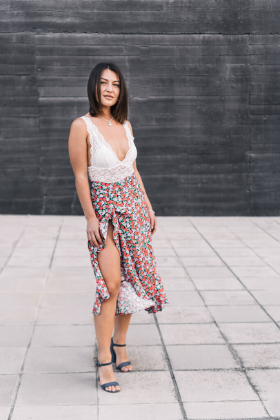 Woman in stylish summer clothes and high heels looking at the camera while posing outdoors on the street. - Photo, Image