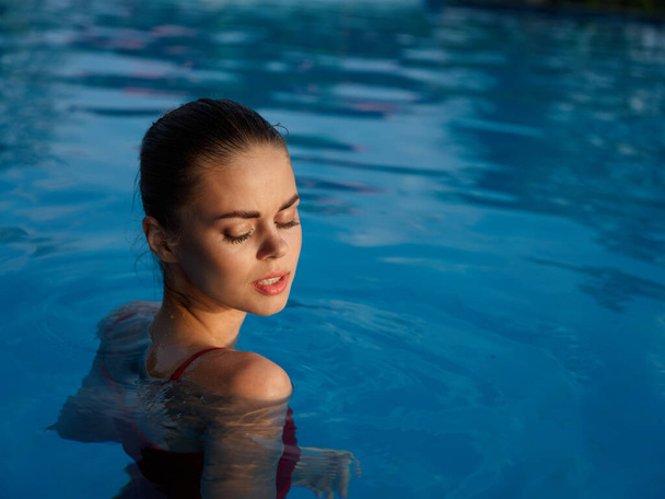 femme nage dans la piscine avec les yeux fermés charme de la nature - Photo, image