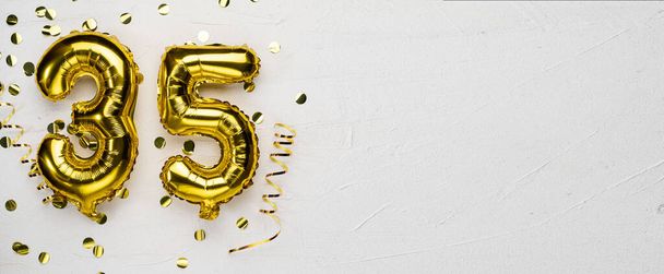 Goldener Folienballon Nummer 35 Geburtstags- oder Jubiläums-Karte mit der Aufschrift 35. grauer Betongrund. Jubiläumsfeier. Banner. Kopierraum - Foto, Bild