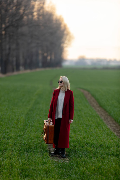 Style blonde woman with suitcase at countryside - Foto, imagen
