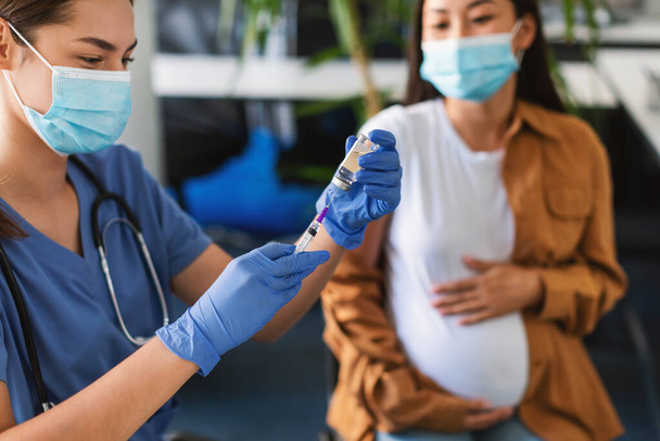 Doctor neemt dosis van Covid-19 Vaccin voor zwangere vrouw - Foto, afbeelding
