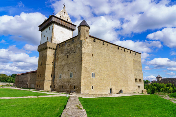 Majesteettinen keskiaikainen linna Narvassa Virossa aurinkoisena päivänä ja taivas pilvissä. - Valokuva, kuva