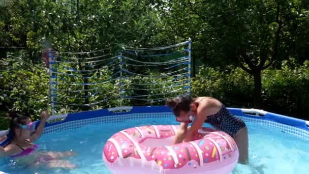 Kinder in Schutzbrillen chillen und tauchen im Sommer gerne durch Donut-Schwimmer im Schwimmbad, tauchen - Filmmaterial, Video