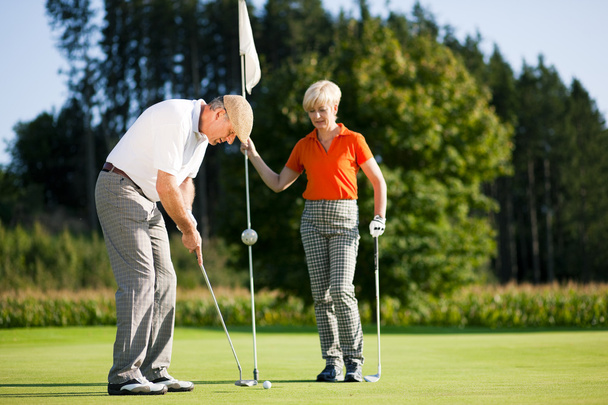 Senior couple playing golf on a - Foto, afbeelding