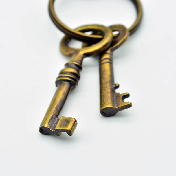 Dettaglio di un portachiavi con diverse vecchie chiavi in metallo, isolato su sfondo bianco - Foto, immagini