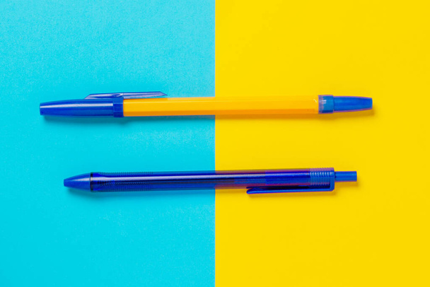 Penna blu e arancione su sfondo blu e giallo. - Foto, immagini